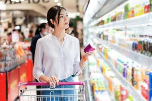 asiatisch Frau gehen zu das Supermarkt zu Kaufen liefert foto