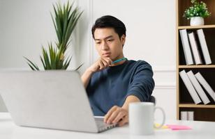 Bild von asiatisch Mann Sitzung beim Zuhause Arbeiten foto