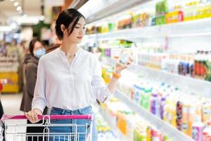 asiatisch Frau gehen zu das Supermarkt zu Kaufen liefert foto