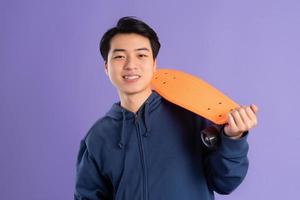 Bild von jung asiatisch Mann spielen Skateboard auf lila Hintergrund foto