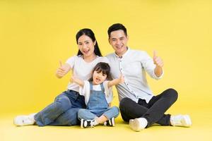 Bild einer asiatischen Familie, die glücklich und isoliert auf gelbem Hintergrund zusammensitzt foto