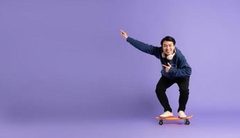 Bild von jung asiatisch Mann spielen Skateboard auf lila Hintergrund foto