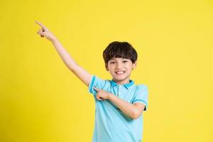 Porträt von ein asiatisch Junge posieren auf ein Gelb Hintergrund foto