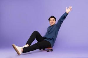 Bild von jung asiatisch Mann spielen Skateboard auf lila Hintergrund foto