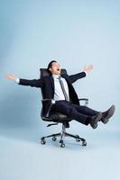asiatisch Geschäftsmann männlich Porträt Sitzung auf Stuhl und isoliert auf Blau Hintergrund foto