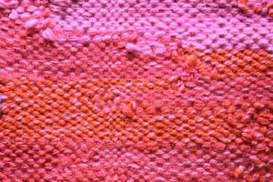 gewebte Rosa und Orange wolle Stoff Textur. Hand gestrickt Textil- Segeltuch Hintergrund. Patchwork Teppich Hintergrund. Fabrik Material Fäden. abstrakt Design. Nahaufnahme, Attrappe, Lehrmodell, Simulation, oben Aussicht foto