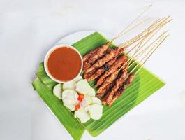 Hähnchen Satay oder Hähnchen Satay serviert mit lange, Reis Kuchen und Erdnuss Soße. serviert auf Banane verlassen foto