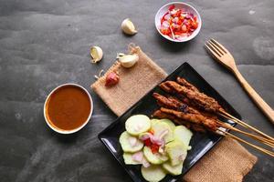 Hähnchen Satay oder stillen Ayam serviert mit lange, Reis Kuchen und Erdnuss Soße. foto