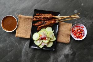 Hähnchen Satay oder stillen Ayam serviert mit lange, Reis Kuchen und Erdnuss Soße. foto