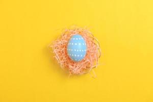 glücklich Ostern Feier Urlaub. Blau Pastell- gemalt Eier im Korbweide Korb Nest Dekoration auf ein Gelb Hintergrund. saisonal Gruß Geschenk Karte Konzept. oben Sicht, eben legen, Kopieren Raum. foto