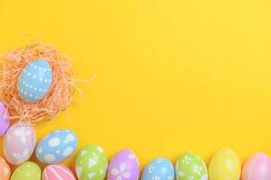 glücklich Ostern Feier Urlaub. bunt Pastell- gemalt Eier im Korbweide Korb Nest Dekoration auf ein Gelb Hintergrund. saisonal Gruß Geschenk Karte Konzept. oben Sicht, eben legen, Kopieren Raum. foto