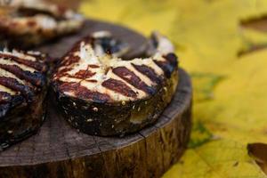 Fischsteaks gebraten auf dem Grill, der auf Baumstamm liegt foto