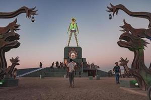 Menschen Gehen gegenüber Sonnenuntergang beim ein Festival im das Wüste beim das Verbrennung Mann Festival. foto