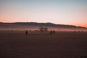 Menschen Gehen gegenüber Sonnenuntergang beim ein Festival im das Wüste beim das Verbrennung Mann Festival. foto