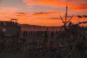 Menschen Gehen gegenüber Sonnenuntergang beim ein Festival im das Wüste beim das Verbrennung Mann Festival. foto