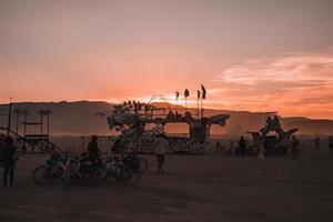 Menschen Gehen gegenüber Sonnenuntergang beim ein Festival im das Wüste beim das Verbrennung Mann Festival. foto