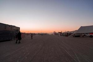 Menschen Gehen gegenüber Sonnenuntergang beim ein Festival im das Wüste beim das Verbrennung Mann Festival. foto