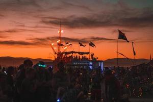 Menschen Gehen gegenüber Sonnenuntergang beim ein Festival im das Wüste beim das Verbrennung Mann Festival. foto