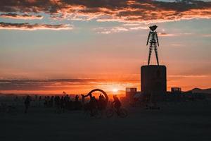 Menschen Gehen gegenüber Sonnenuntergang beim ein Festival im das Wüste beim das Verbrennung Mann Festival. foto