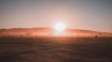 Menschen Gehen gegenüber Sonnenuntergang beim ein Festival im das Wüste beim das Verbrennung Mann Festival. foto