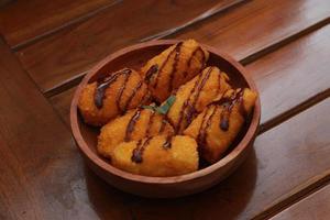 ein schließen oben von Banane Nuggets mit Schokolade Soße Belag serviert auf ein hölzern Schüssel. Essen Konzept Foto. foto