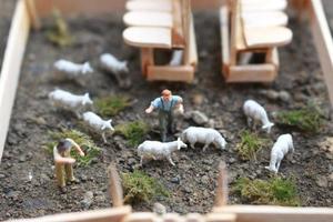 ein schließen oben von Miniatur Zahl von ein Ziege Hirte Fütterung im ein hölzern Käfig. Schäfer Konzept. foto