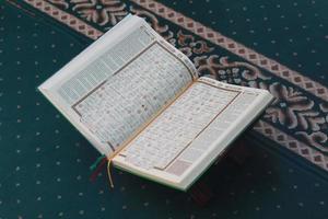 ein schließen oben von das heilig Buch al-Koran auf ein Grün Gebet Teppich. islamisch Foto Konzept.