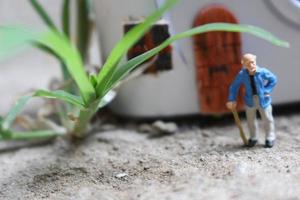 Miniatur Zahl von ein Großvater Wer ist warten im Vorderseite von das Haus. foto