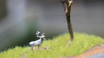 Miniatur Zahl von ein Elch Essen. ein Wiese und Baum Diorama. Konzept von Natur und Tiere. foto