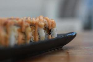 japanisch Essen namens Lachs Mozza Sushi. serviert warm auf ein schwarz rechteckig Teller auf das Tisch. foto