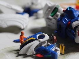 Miniatur Zahl von ein Techniker reparieren ein gebrochen Roboter Hand. foto