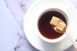 Tasse Tee und braune Zuckerwürfel auf dem Tisch foto
