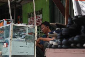 ein Uhr Handwerker war warten zum ein Kunde beim seine wenig Stand durch das Straßenrand. ein einzigartig Beruf von Indonesien. foto