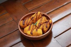 ein schließen oben von Banane Nuggets mit Schokolade Soße Belag serviert auf ein hölzern Schüssel. Essen Konzept Foto. foto