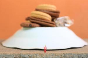 Miniatur Zahl von ein Kind suchen oben beim das Berge gemacht von ein Teller und etwas Kuchen. foto