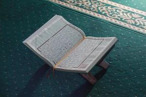 ein schließen oben von das heilig Buch al-Koran auf ein Grün Gebet Teppich. islamisch Foto Konzept.
