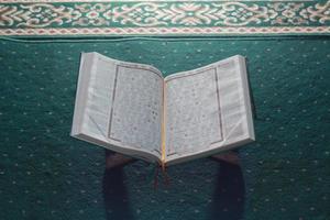 ein schließen oben von das heilig Buch al-Koran auf ein Grün Gebet Teppich. islamisch Foto Konzept.