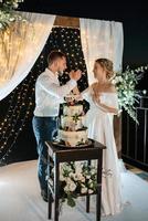 Jungvermählten schneiden glücklich die Hochzeitstorte an und probieren sie foto