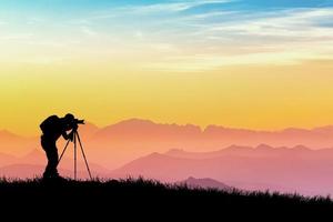 Die Silhouette eines professionellen Fotografen konzentriert sich auf das Fotografieren auf einer wunderschönen Wiese. foto