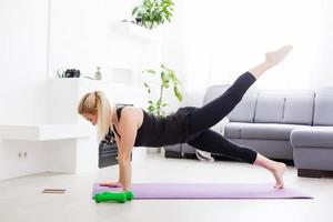 Konzept von gesund Lebensstil. schließen oben von jung Frau Hände rollen violett Yoga Fitness Matte Vor Arbeiten aus beim Zuhause im Leben Zimmer. jeder Tag Morgen Ritual. hölzern Boden, Sanft Licht foto