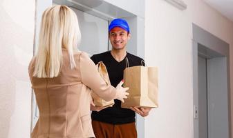 ein gut aussehend jung Lieferung Mann liefern ein Paket zu Wohnung foto