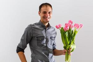 Mann mit Blumen. romantisch Mann mit Strauß von Tulpen zum Geburtstag. glücklich Frau Tag. geben Strauß von Blumen. gut aussehend Mann geben Blumen. Weiß Hintergrund. horizontal Fotos