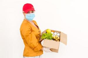 Lieferung Mädchen trägt medizinisch Gesicht Maske und Handschuhe und hält Box Nahansicht Porträt. Konzept von sicher Dienstleistungen während covid-19 Ausbruch. Kurier auf Weiß Hintergrund foto