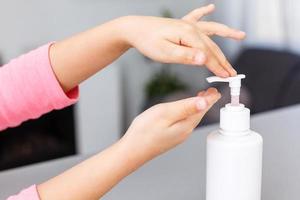 Kind bewirbt sich Gel Desinfektionsmittel auf seine Hände, Schutz gegen Mikroben und Viren. transparent Flüssigkeit Seife benutzt zum Hand Waschen foto