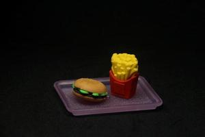 Hamburger und Fritten geformt Radiergummi. Schule oder Büro stationär Werkzeug liefert mit Müll Essen Form. isoliert Foto auf dunkel schwarz Hintergrund.