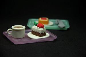 Süss zuckerhaltig Essen geformt Radiergummi. Schule oder Büro stationär Werkzeug liefert mit Süss Schokolade und ausgepeitscht Sahne Kuchen mit Erdbeere Belag Form. isoliert Foto auf dunkel schwarz Hintergrund.