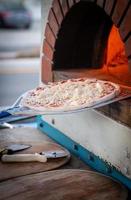 Platzierung Pizza in Backstein Ofen foto