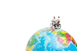 Miniaturreisende mit Fahrrädern auf einem Globus auf einem weißen Hintergrund foto