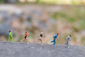 Miniaturmenschen, die auf einem Felsen-, Gesundheits- und Lebensstilkonzept laufen foto