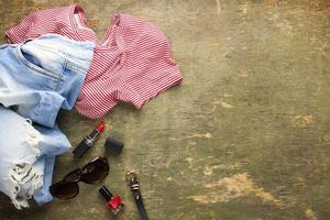 Sommer- Damen Kleidung und Zubehör T-Shirt, Jeans, Lippenstift, Nagel Polieren, Gürtel, Sonnenbrille. oben Sicht. foto